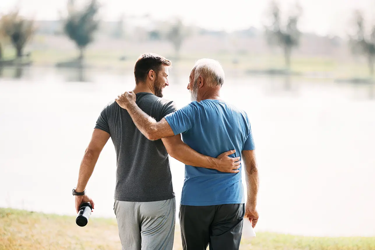 Younger and older man walking together by lake, symbolizing financial planning guidance in Spring, TX.