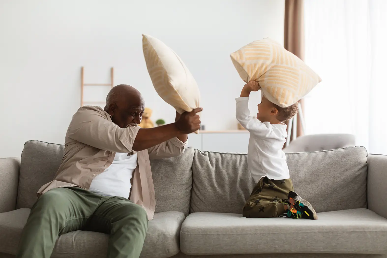 Grandfather and grandson having a playful pillow fight on the couch, capturing family legacy and love in Spring, TX.