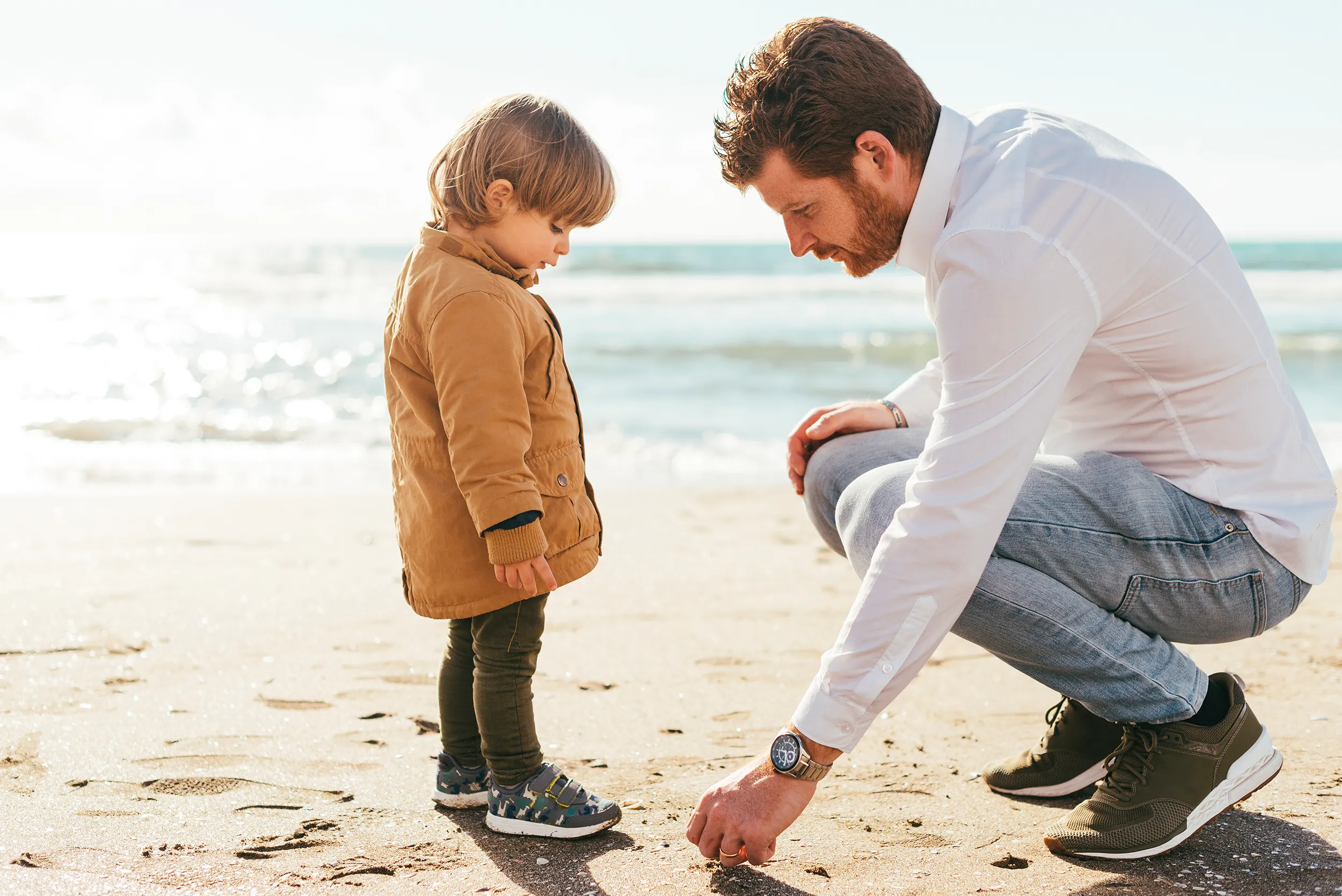 Parent teaching a young child at the beach, representing long-term investment planning for the future